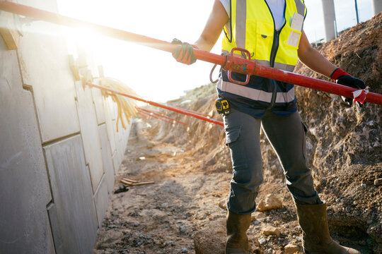 Female construction worker checking site line with tool