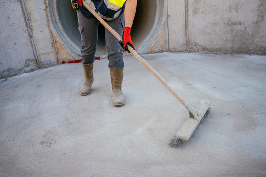 Construction worker woman sweeping concrete drainage tunnel