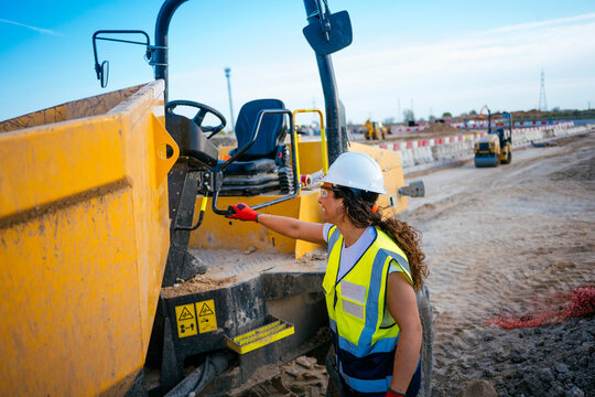 Female construction worker inspecting heavy equipment on site