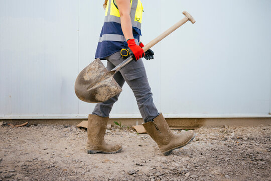 Construction worker woman carrying shovel on job site