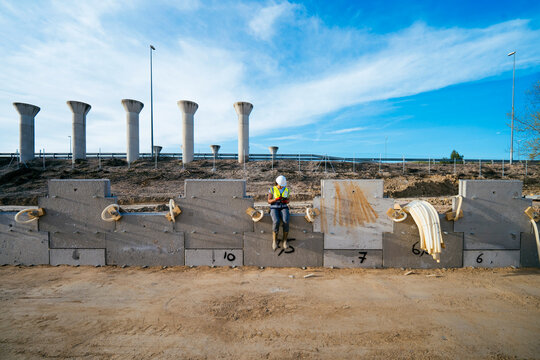 Female construction worker resting by concrete barriers