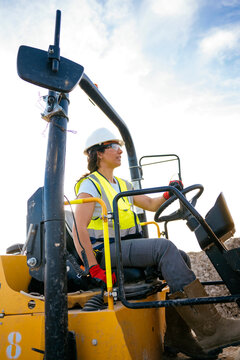 Female construction worker operating loader at job site