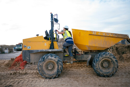 Woman construction worker climbing dumper truck at work