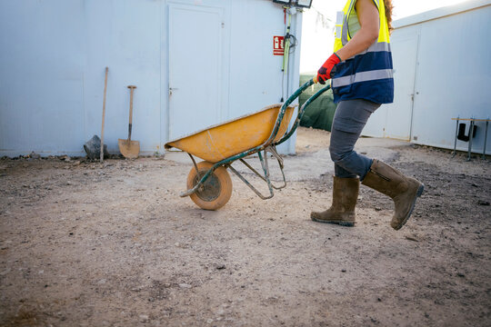 Female construction worker pushing wheelbarrow on job site