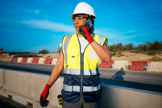 Woman construction worker using smartphone at roadside site