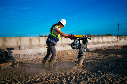 Female construction worker using rammer compactor outdoors
