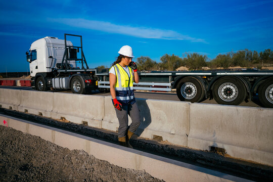 Woman construction worker walking by truck at road site