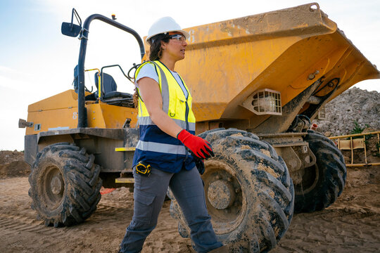 Female construction worker walking by dumper on site