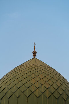 Green mosque dome with crescent against clear sky, Uzbekistan