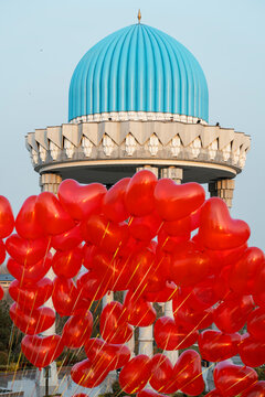 Red heart balloons in front of a blue dome in Uzbekistan