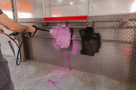 Self-service car mat wash with foam spray at car wash bay