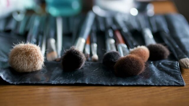 Makeup brushes arranged in a roll case on a wooden table