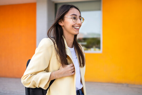 Young woman smiling outdoors with colorful wall background