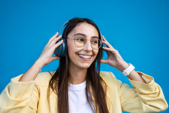 Young woman smiling with headphones on colorful background