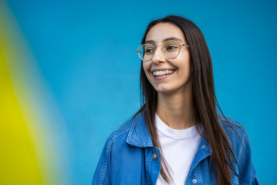Smiling young woman with glasses on colorful background