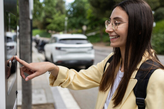 Young woman paying for street parking at a modern meter