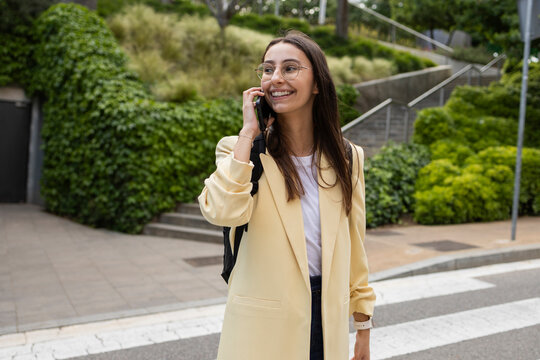 Young woman smiling on phone call in urban park walkway