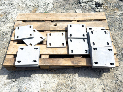 Steel base plates on pallet at construction site with rebar