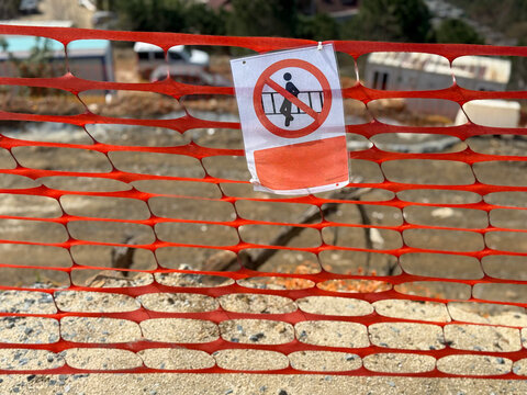 Warning sign on orange safety fence at construction site