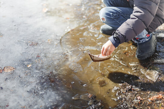 Boy playing with a boat in early spring park