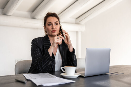 Businesswoman multitasking with laptop and phone in office
