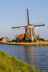 Naklejka premium Dutch windmill standing by canal in Heerhugowaard, Netherlands