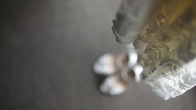 Blurred white shoes beside lace fabric on dark floor