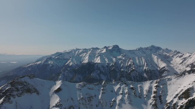 Drone footage of snow covered mountain ridges and rocky peaks near Galina Peak, above Arshan village, Republic of Buryatia, Russia, on a clear winter day