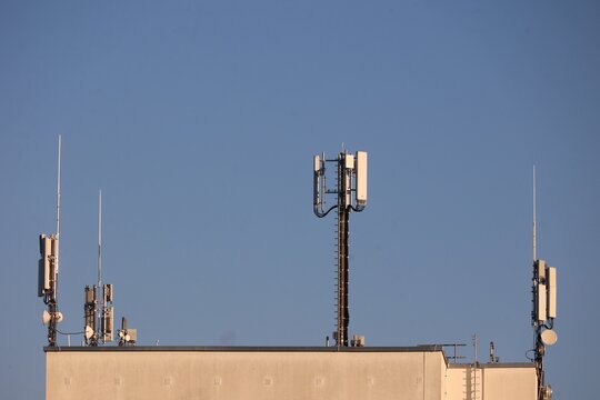 Telecommunication Antennas on Building Rooftop Against Blue Sky