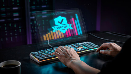 Fototapeta premium IT professional typing on a keyboard with a futuristic holographic dashboard showing a verified security shield and data analytics bar charts.