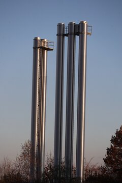 Industrial Pipes Against Blue Sky with Tree Branches