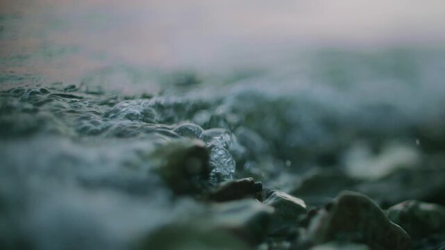 Wet dark rocks beside softly rippling water