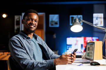 Fototapeta premium African american advisor navigating on smartphone network, checking social media apps before solving economic and financial assignments. Male specialist taking a break from remote work.