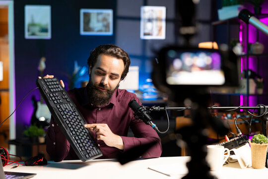 Influencer filming keyboard review in apartment, showing typing capabilities. Technology guru showcasing computer peripheral to audience on niche online channel, looking at functionalities