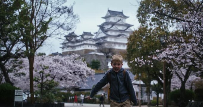 Silhouette of child making silly faces in front of spring cherry blossoms near ancient Himeji castle