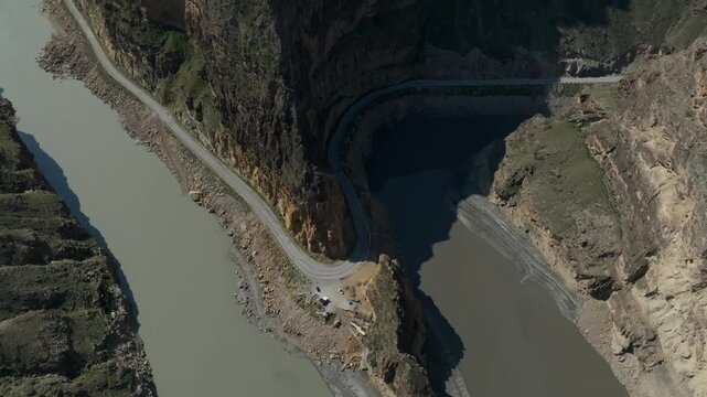 Drone footage of the confluence of the Avar Koysu and Andi Koysu rivers in a rocky mountain canyon, Dagestan, Russia, with a winding road along the riverbank