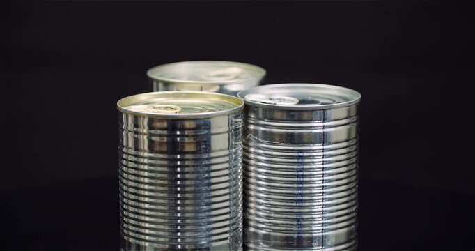 Three reflective metal cans on a dark studio background