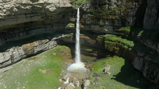 Aerial footage of Tobot Waterfall dropping into a deep rocky canyon on the Khunzakh Plateau, Republic of Dagestan, Russia, with green cliffs and misty spray