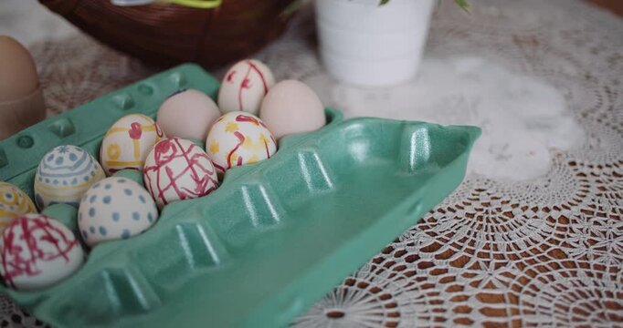 Decorated Easter eggs in a green carton on a lace table