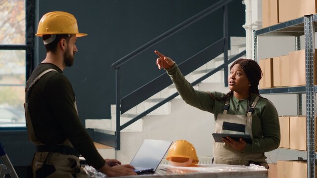 Warehouse head of operations carrying out the logistics of receiving, processing, storing and sending inventory according to purchase orders and shipping schedules, requesting help from employee