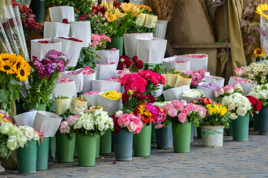 Small flower bouquets displayed for sale on a busy street, colorful fresh blossoms arranged by vendor, urban marketplace atmosphere, seasonal floral trade, and outdoor commerce concept.