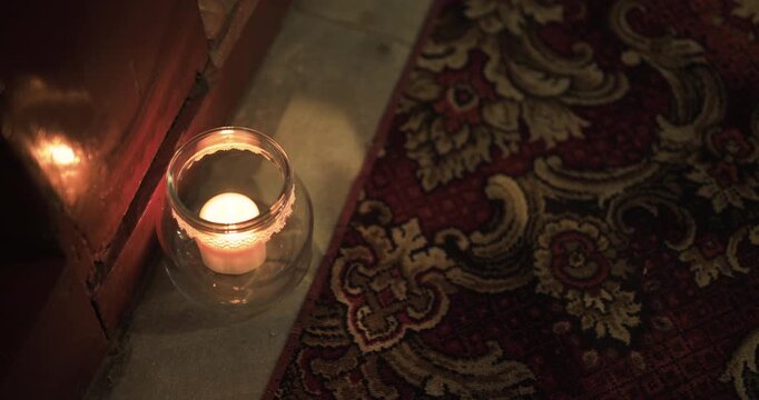 Warm candlelight beside a patterned rug in a cozy interior