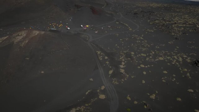 Aerial footage of the Tolbachinsky Dol Northern Breakthrough lava fields and volcanic cones under low clouds in Kamchatka Krai, Russia, remote wilderness scenery