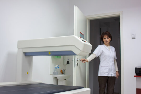 Woman nurse opening door of bone densitometry room in medical clinic density scanning machine