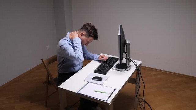 Man suffering from neck and shoulder pain while working long hours at a computer in a home office, highlighting workplace discomfort, poor ergonomics, and health issues from extended screen time