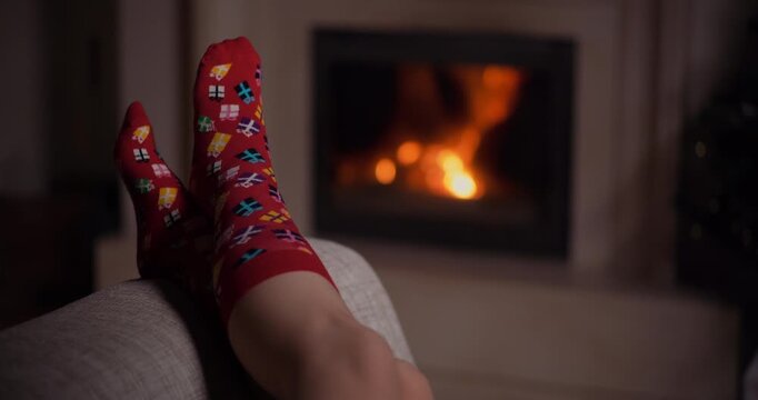 Sock-covered foot resting by a glowing fireplace