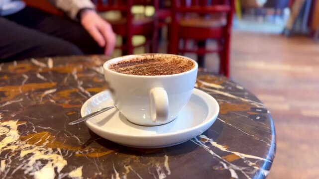 hot beverage coffee in white cup with saucer and teaspoon on coffee shop table