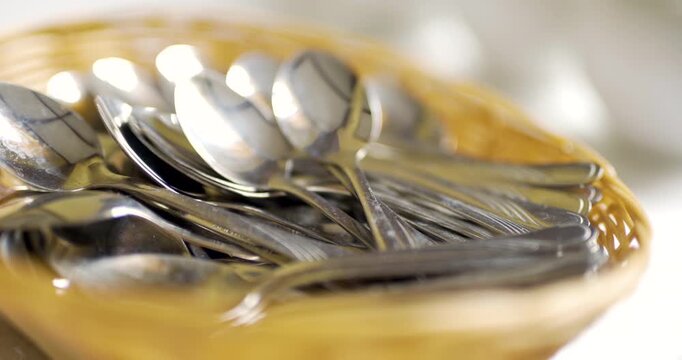 Shiny metal spoons in a woven basket on a tabletop