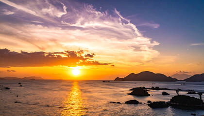 Naklejka premium Vibrant sunset over the ocean with scattered clouds and silhouetted islands, reflecting golden light on the water