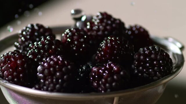 Fresh blackberries being rinsed in a metal colander